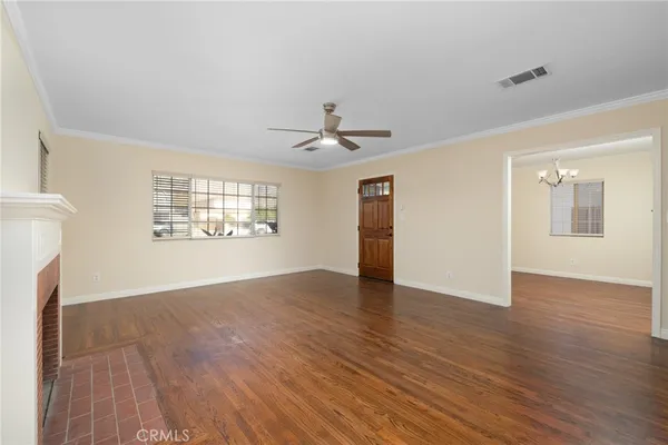 a view of an empty room with a window and wooden floor