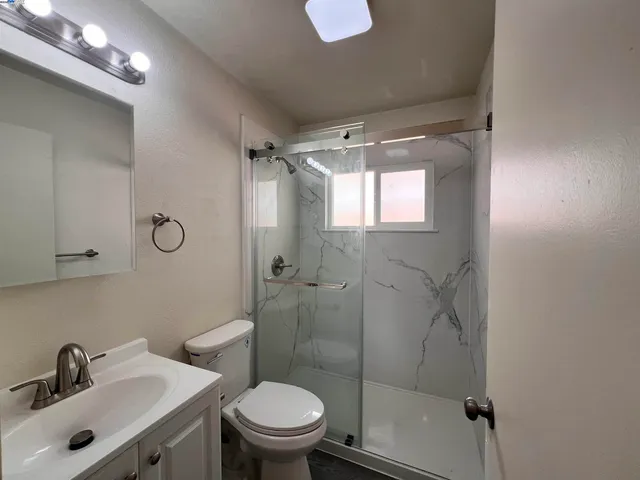 a bathroom with a shower sink mirror and toilet