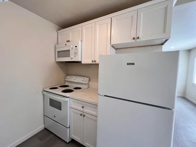 a kitchen with white cabinets and white appliances