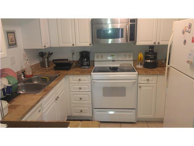 8242 Severn Drive, Unit A Boca Raton, FL 33433 - Photo 7 of 11 a kitchen with a stove a sink and a microwave