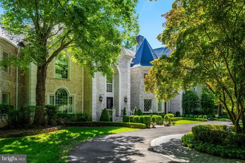 a view of a brick house with a big yard plants and large trees