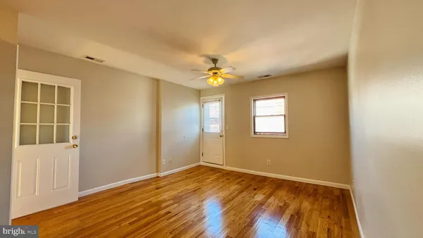 an empty room with wooden floor and windows