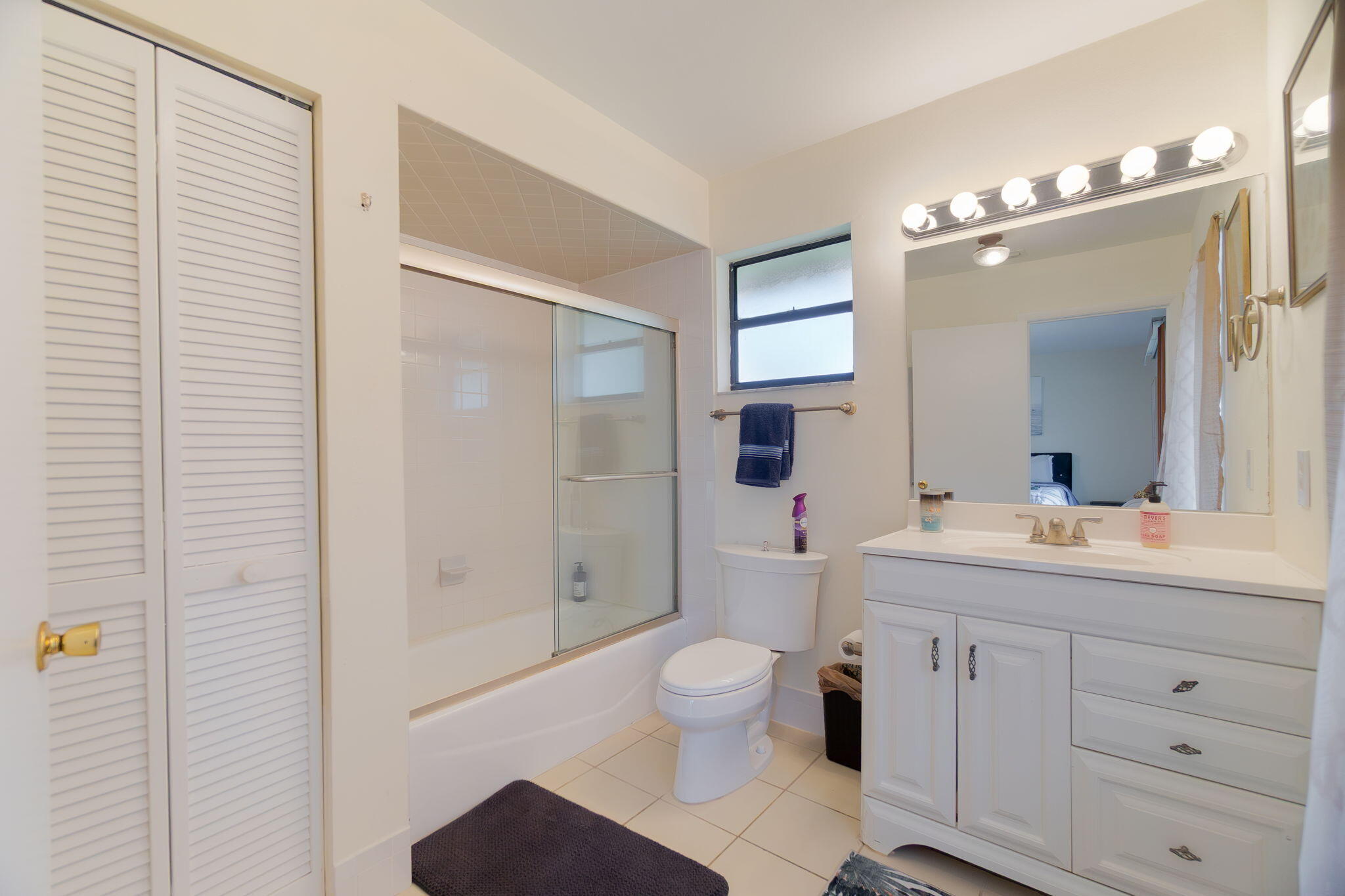 6130 Francis Street Jupiter, FL 33458 - Photo 9 of 27 a bathroom with a toilet a sink a mirror a shower a vanity and window
