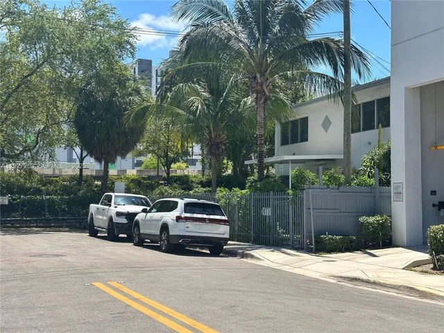 a view of street with small yard and wooden fence