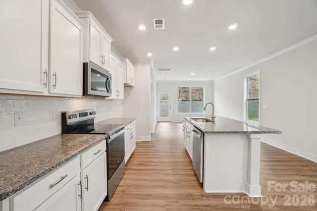 a kitchen with stainless steel appliances granite countertop a sink a stove and cabinets