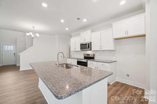 a kitchen with granite countertop white cabinets and stainless steel appliances