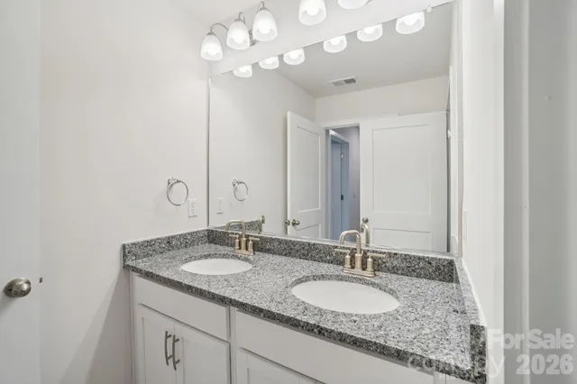 a bathroom with a granite countertop double vanity and a mirror