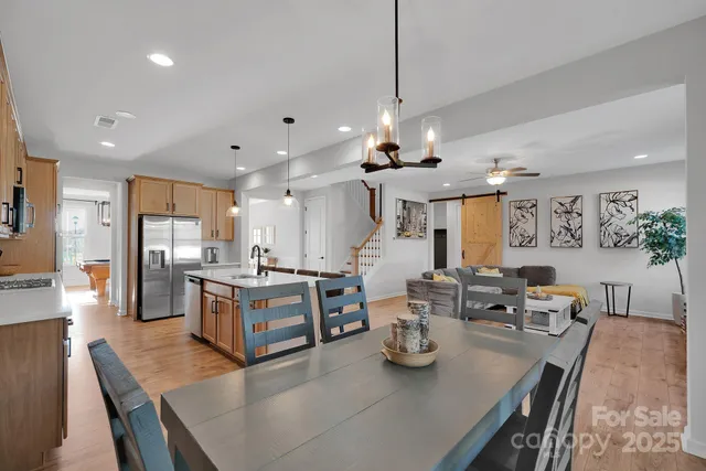 a large kitchen with sink a refrigerator and chairs