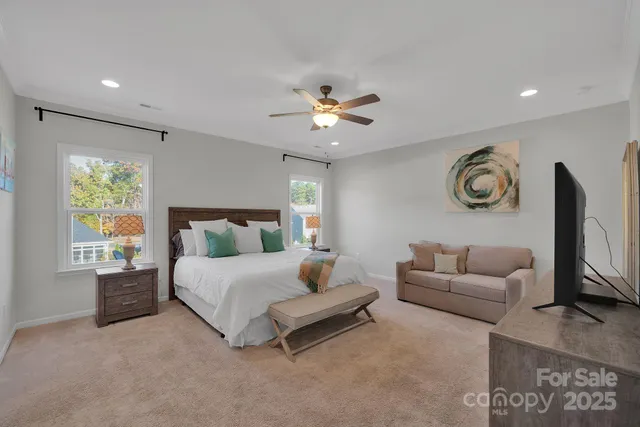 a spacious bedroom with a bed furniture chandelier and a window