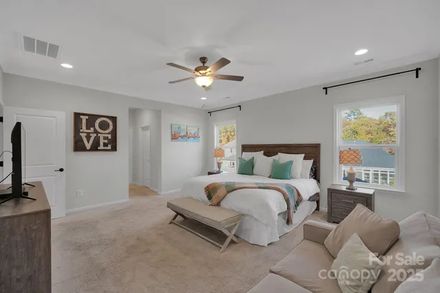 a spacious bedroom with a bed painting on wall and a flat screen tv