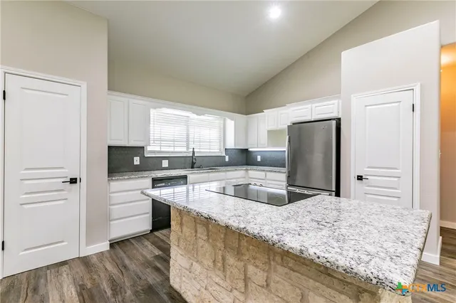 an open kitchen with fireplace and wooden floor