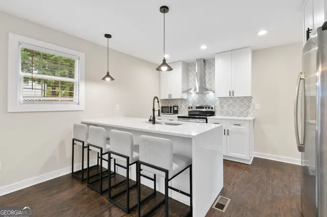 a kitchen with stainless steel appliances granite countertop a stove a sink refrigerator and a wooden floor