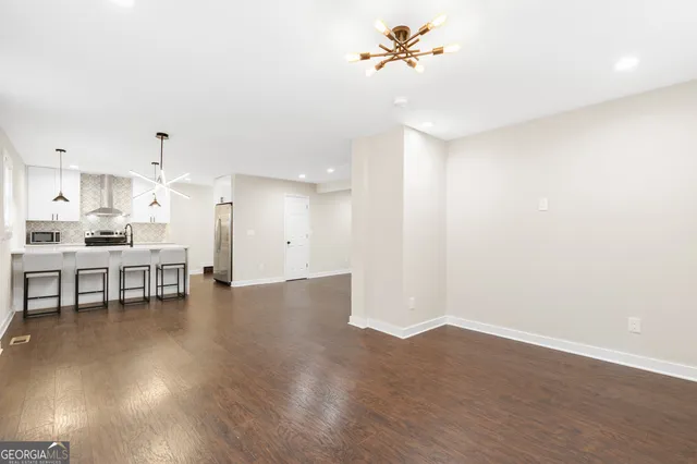 a view of a room with wooden floor and a kitchen