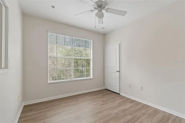 an empty room with wooden floor chandelier fan and windows