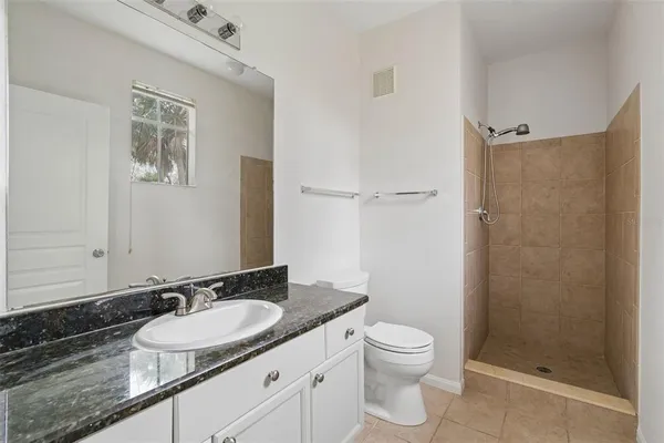 a bathroom with a granite countertop sink toilet a mirror and shower