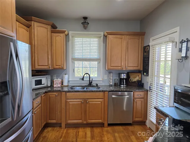 a kitchen with stainless steel appliances granite countertop a sink a stove a refrigerator cabinets and a window