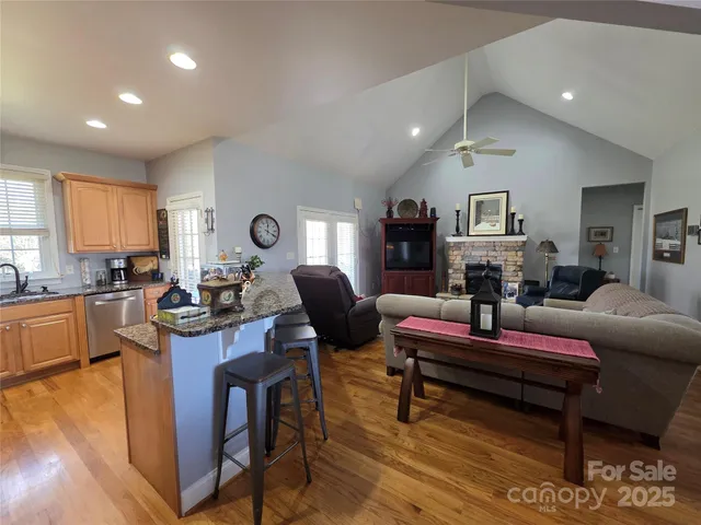 a living room with furniture a rug kitchen view and a large window
