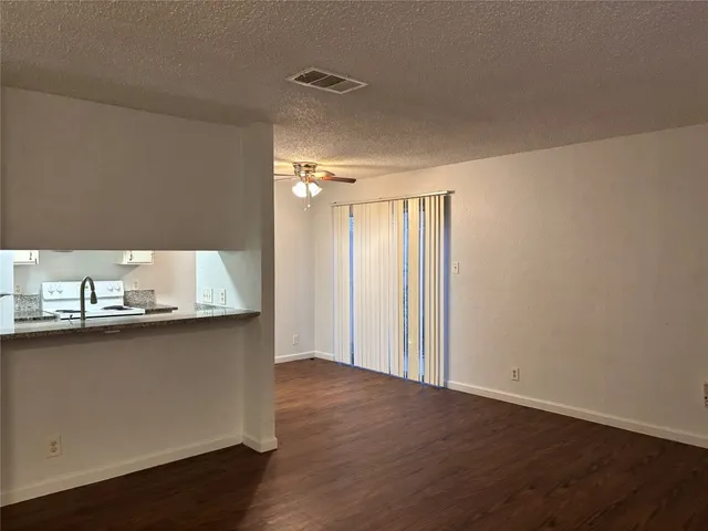 an empty room with wooden floor and kitchen view