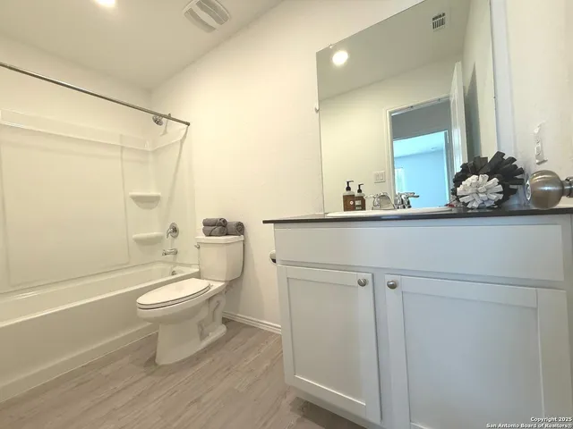a bathroom with a toilet a sink and wooden floor