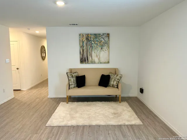 a large bed sitting in a room next to a bathroom with a sink and wooden floor