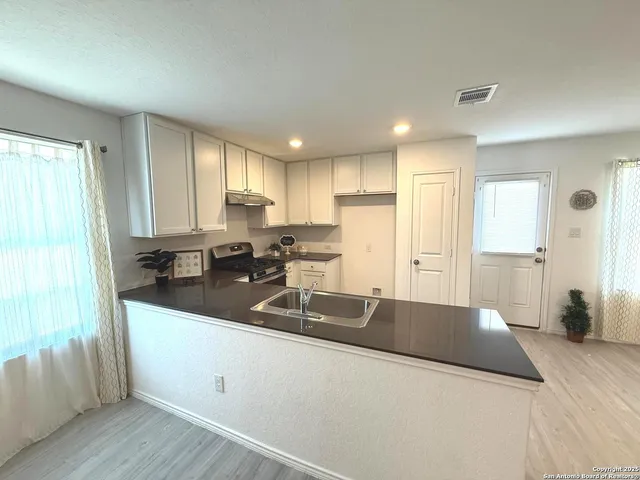 a kitchen with stainless steel appliances granite countertop a sink a stove and a refrigerator