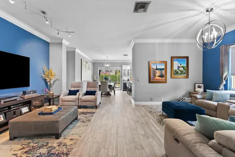 a living room with furniture a flat screen tv and a chandelier