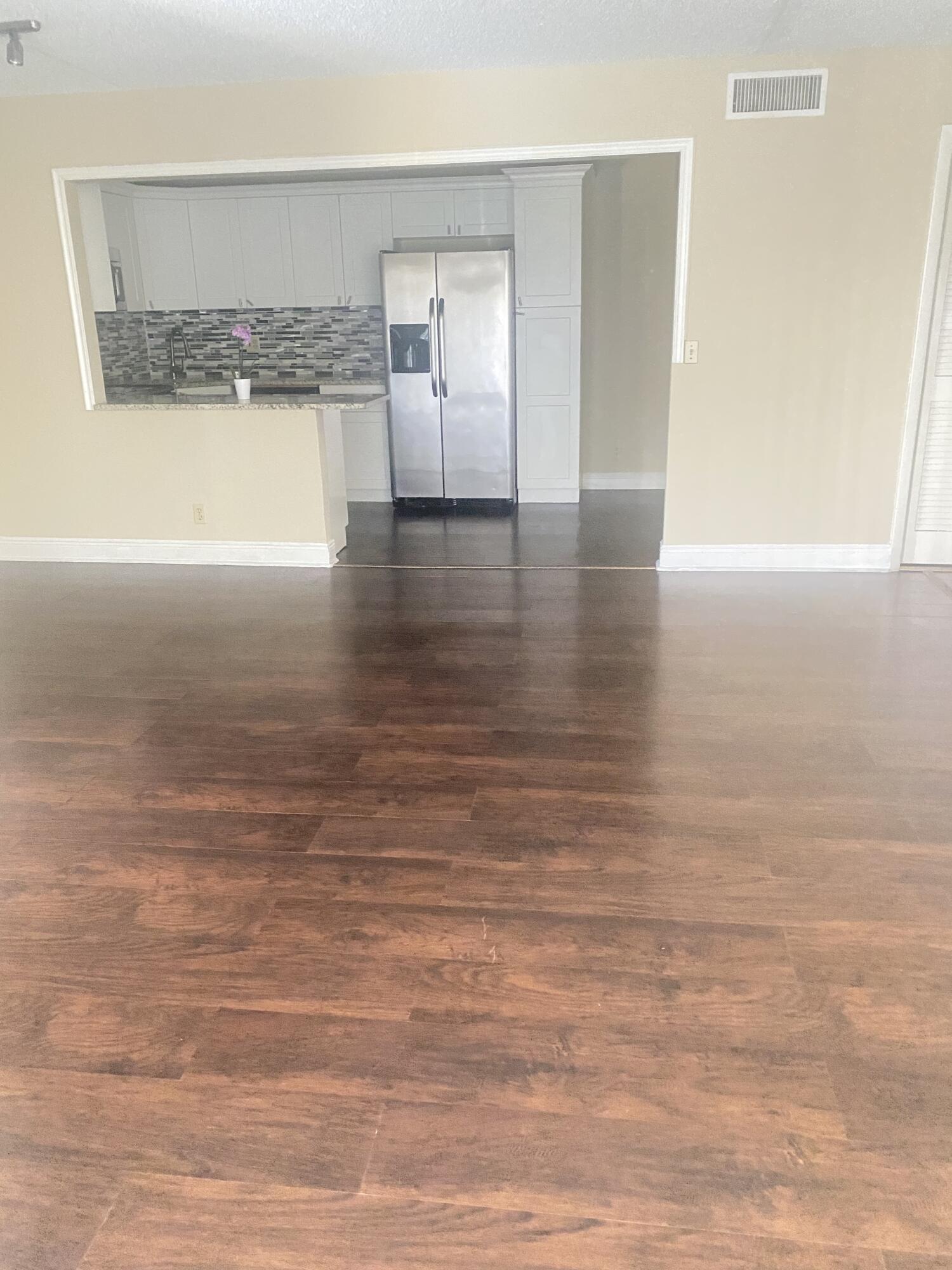 1010 Green Pine Boulevard, Unit D1 West Palm Beach, FL 33409 - Photo 2 of 5 a view of an empty room and kitchen with wooden floor