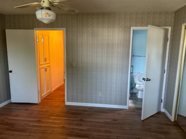 a view of empty room with wooden floor and fan