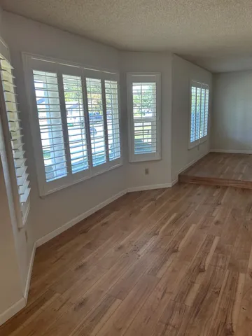 a view of an empty room with wooden floor and a window