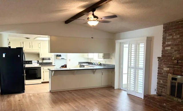 a kitchen with stainless steel appliances granite countertop a refrigerator a sink dishwasher a stove and white countertops with wooden floor