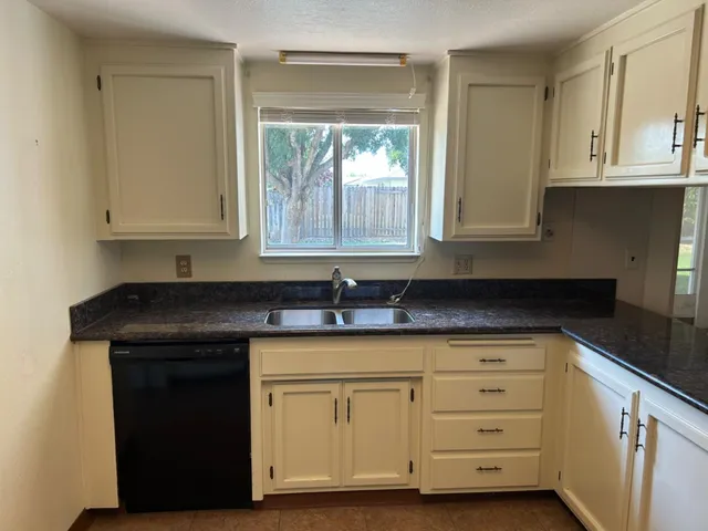 a kitchen with granite countertop a sink cabinets and window