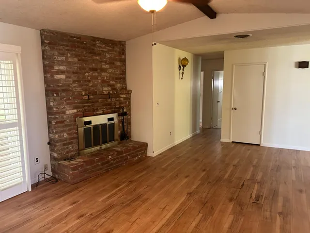 an empty room with wooden floor a fireplace and windows