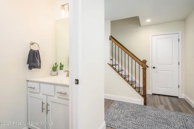a view of a hallway with white walls and stairs
