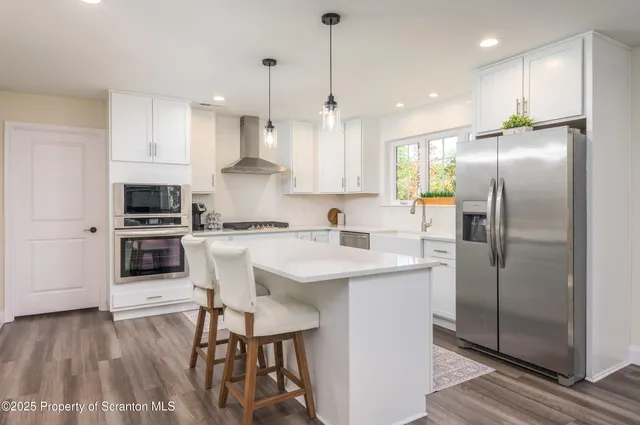 a kitchen with kitchen island white cabinets and stainless steel appliances