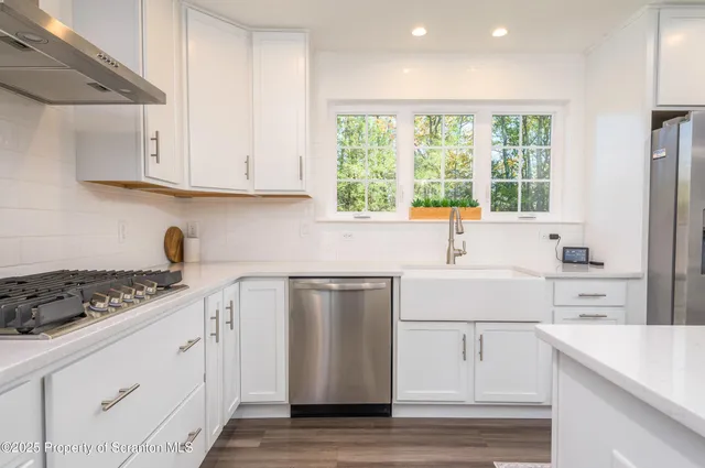 a kitchen with stainless steel appliances white cabinets and a stove top oven