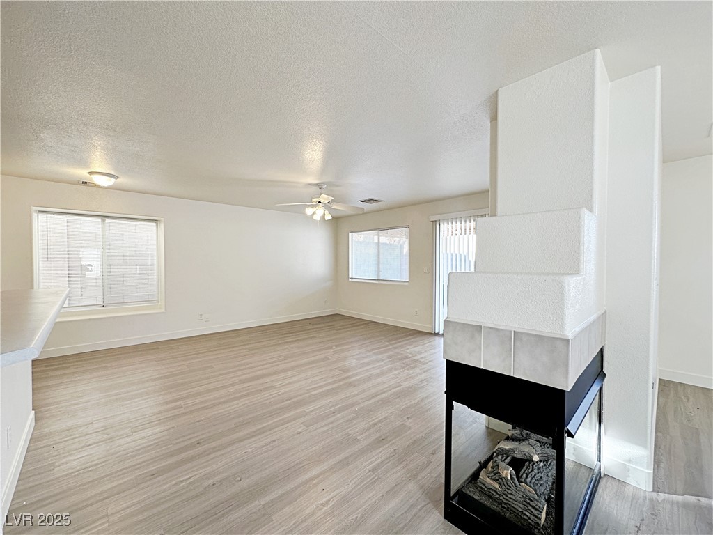 9416 Moon Splash Court Las Vegas, NV 89129 - Photo 11 of 47 Unfurnished living room featuring light wood-style flooring, a textured ceiling, and ceiling fan
