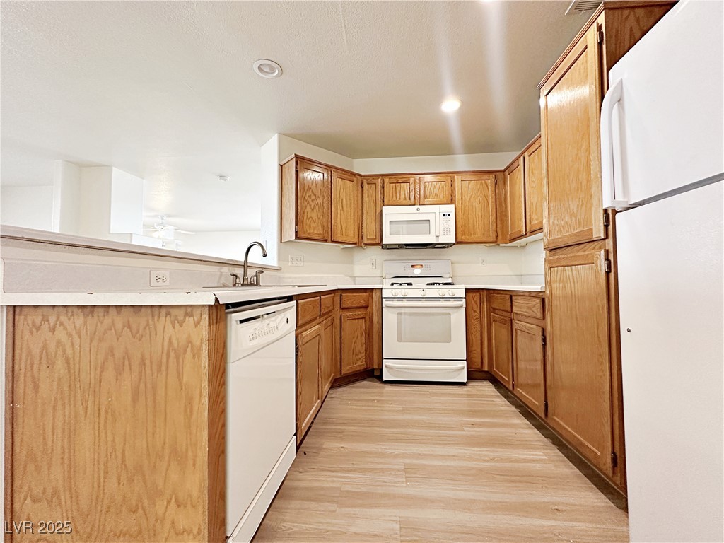 9416 Moon Splash Court Las Vegas, NV 89129 - Photo 17 of 47 Kitchen featuring white appliances, light wood-type flooring, light countertops, brown cabinets, and recessed lighting
