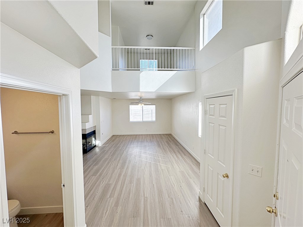 9416 Moon Splash Court Las Vegas, NV 89129 - Photo 6 of 47 Unfurnished living room with a high ceiling, light wood-style flooring, healthy amount of natural light, and a fireplace