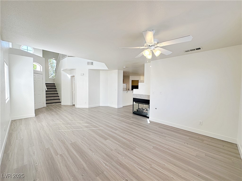 9416 Moon Splash Court Las Vegas, NV 89129 - Photo 9 of 47 Unfurnished living room with stairway, light wood-type flooring, and ceiling fan