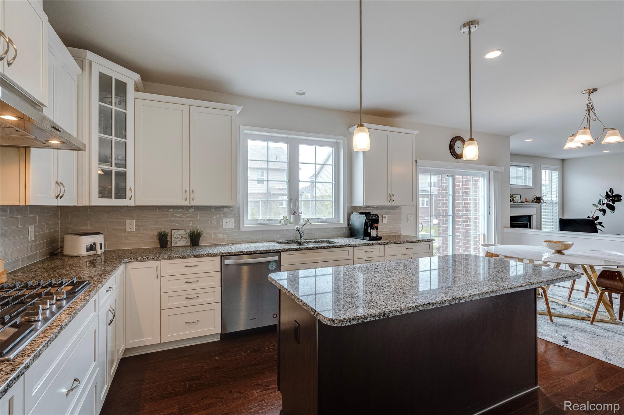 51011 Rockingham Drive Canton, MI 48188 - Photo 11 of 74 Kitchen featuring decorative backsplash, dark wood finished floors, light stone counters, a center island, and stainless steel appliances