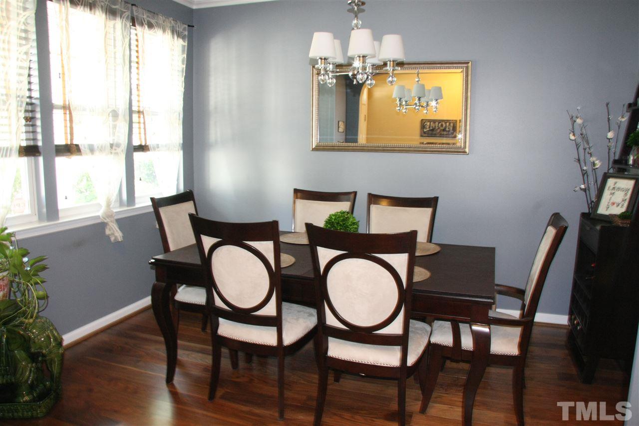 8305 Rubblestone Path Raleigh, NC 27613 - Photo 4 of 24 a dining room with furniture a chandelier and wooden floor