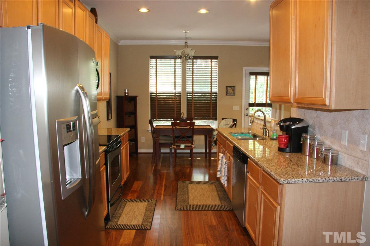 8305 Rubblestone Path Raleigh, NC 27613 - Photo 5 of 24 a kitchen with stainless steel appliances granite countertop a refrigerator a stove a sink dishwasher and a dining table with wooden floor
