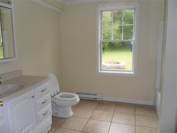 706 Main Street Boxford, MA 01921 - Photo 22 of 26 a bathroom with a granite countertop sink a toilet and a window