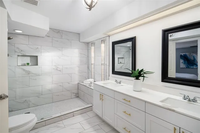 a bathroom with a double vanity sink mirror and shower
