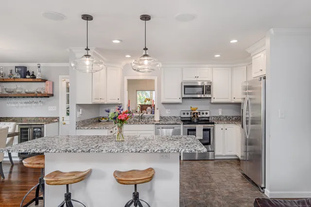 a kitchen with stainless steel appliances granite countertop a stove top oven a sink a dining table and chairs