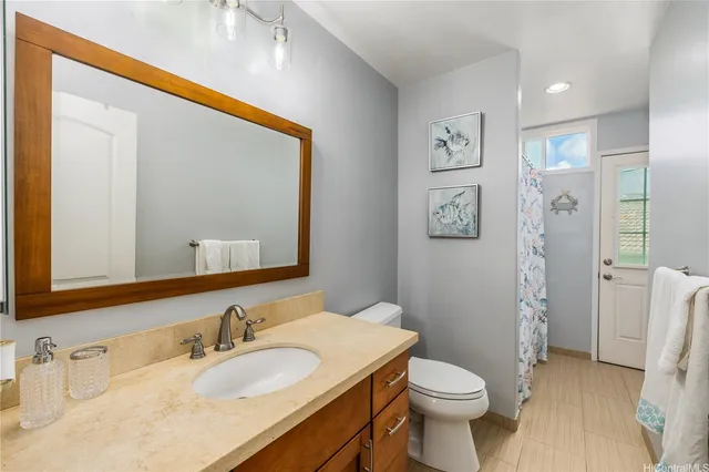 a bathroom with a granite countertop toilet sink and mirror