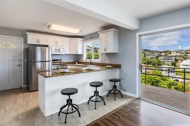 a kitchen with stainless steel appliances granite countertop a refrigerator a sink a stove a dining table and chairs with wooden floor