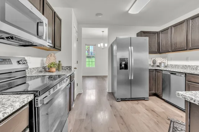 a kitchen with stainless steel appliances granite countertop a refrigerator a stove and a sink with wooden cabinets