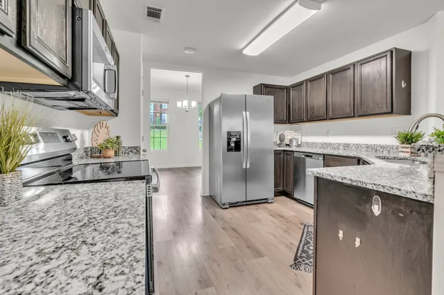 a kitchen with stainless steel appliances granite countertop a refrigerator a stove and a sink