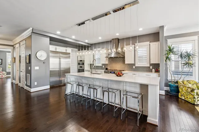 a dining room with wooden floor a chandelier a glass table and chairs